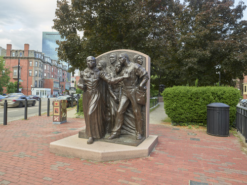 A bronze sculpture of Harriet Tubman leading a group to the north. Created in 1999 at Harriet Tubman Park in Boston's South End by Fern Cunningham, this is the first public sculpture in Boston on city-owned land depicting a woman. In the sculpture, Harriet Tubman appears to be striding and holds a bible in her right arm. Her left arm is held out as she leads theway. Behind her, five men and women of various ages appear to be mid-stride. One young woman with braids and a dress leans her head on a man's shoulder, whose free hand reaches into his satchel. The other people appear to be looking calmly in different directions.